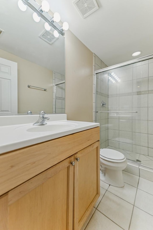 bathroom featuring tile patterned flooring, vanity, a shower with shower door, and toilet