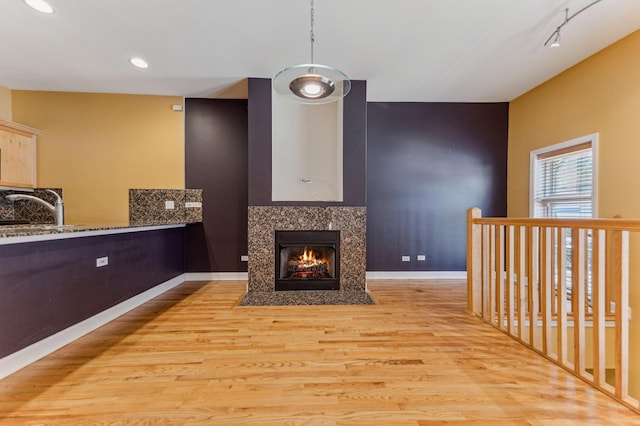 living room featuring track lighting, a premium fireplace, light hardwood / wood-style floors, and sink