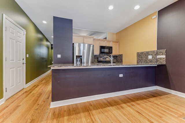 kitchen with light brown cabinetry, tasteful backsplash, appliances with stainless steel finishes, kitchen peninsula, and light hardwood / wood-style floors