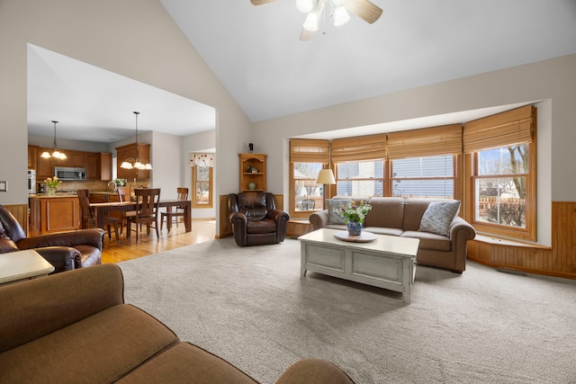 living room featuring high vaulted ceiling, ceiling fan with notable chandelier, and light carpet