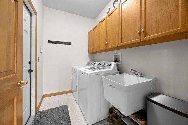 laundry area featuring washing machine and clothes dryer, cabinet space, baseboards, and a sink