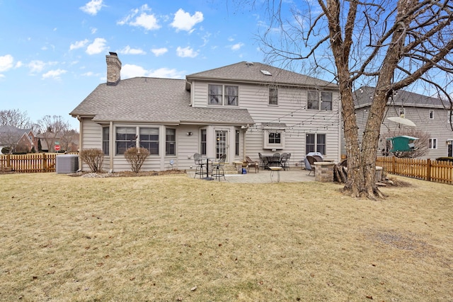 rear view of property featuring central air condition unit, a lawn, a chimney, a fenced backyard, and a patio