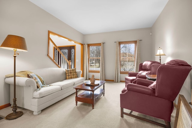 living area featuring stairway, light colored carpet, and baseboards