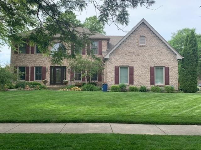 colonial house featuring brick siding and a front lawn