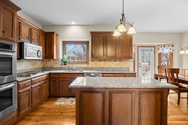 kitchen featuring a sink, light wood-type flooring, tasteful backsplash, and appliances with stainless steel finishes