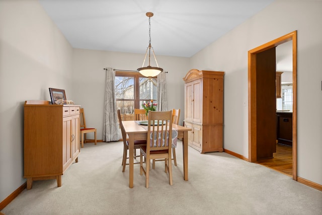 dining space featuring baseboards and light colored carpet