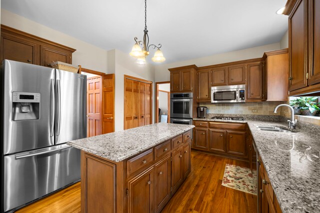 kitchen featuring a sink, backsplash, dark wood-style floors, a center island, and appliances with stainless steel finishes