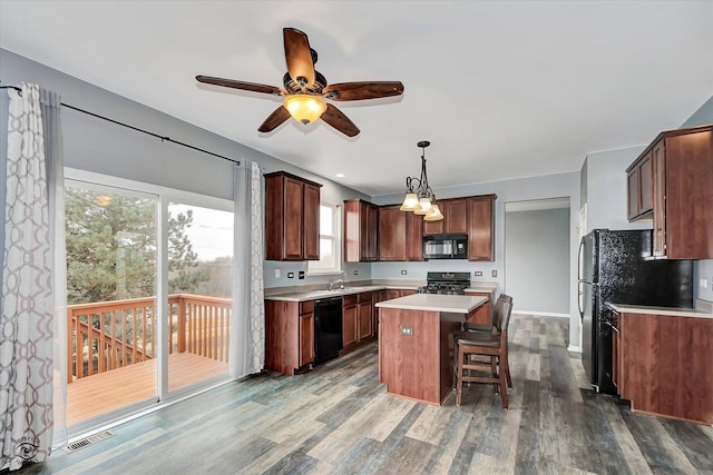 kitchen featuring wood finished floors, visible vents, black appliances, light countertops, and a center island