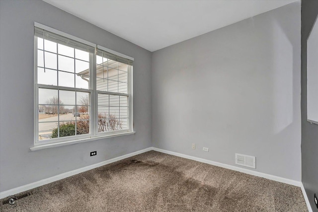 spare room with baseboards, visible vents, and dark colored carpet
