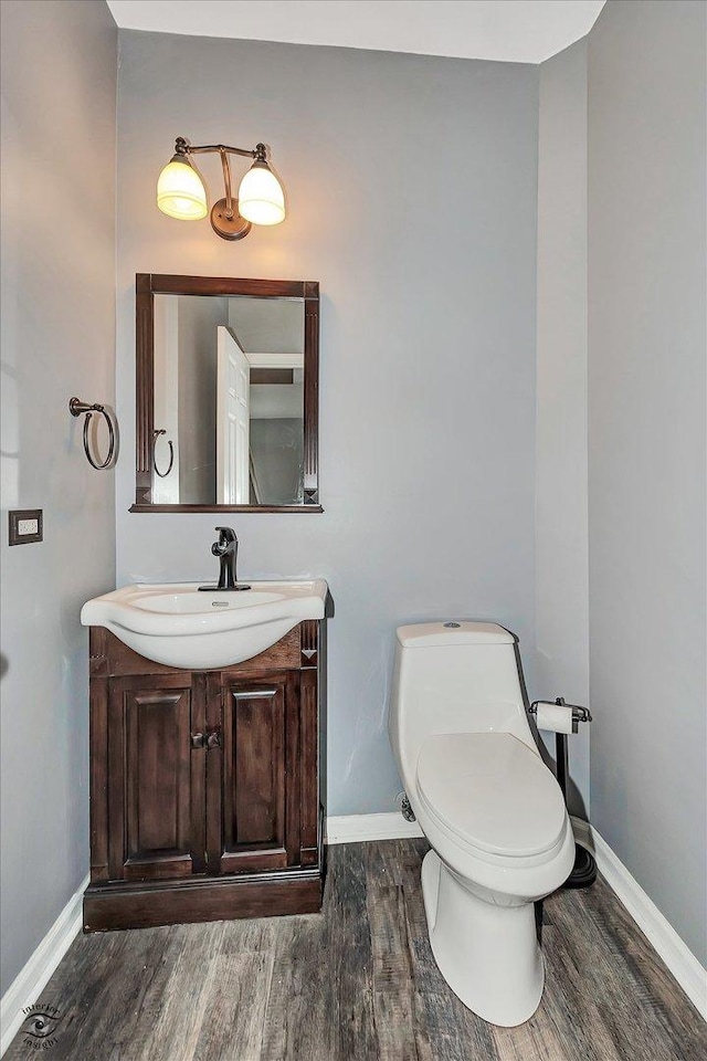 bathroom with baseboards, toilet, wood finished floors, and vanity