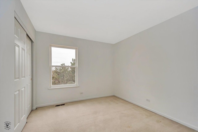 unfurnished bedroom featuring baseboards, visible vents, a closet, and light carpet