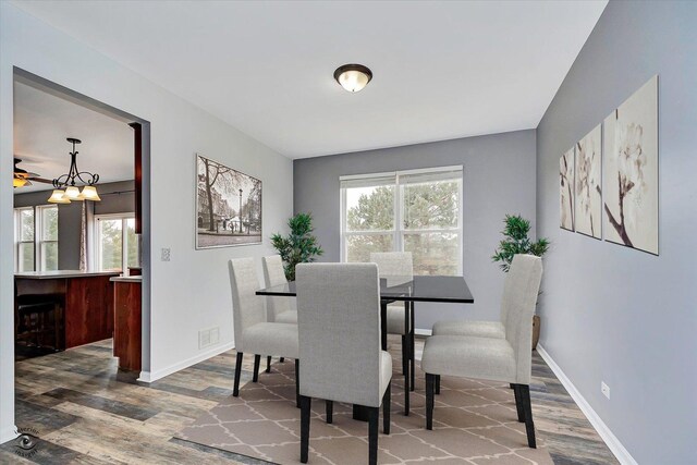 dining room with visible vents, a healthy amount of sunlight, baseboards, and wood finished floors