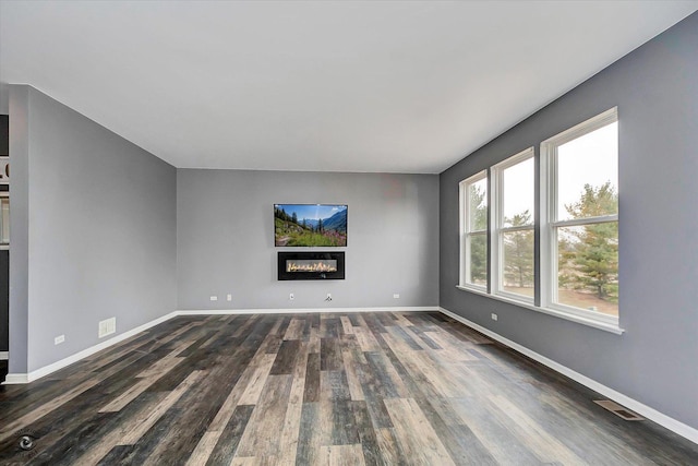 unfurnished living room featuring visible vents, baseboards, and dark wood-style floors
