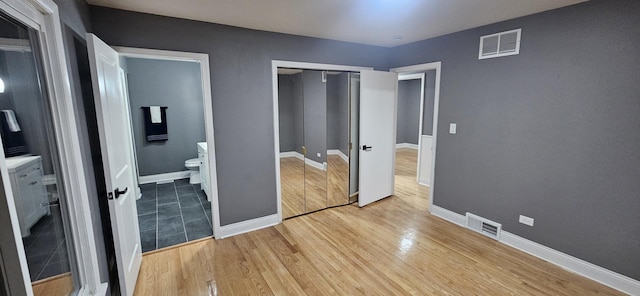 unfurnished bedroom featuring light hardwood / wood-style floors, a closet, and ensuite bathroom