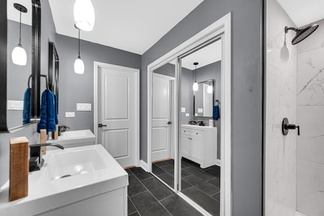 bathroom featuring tile patterned flooring, vanity, and a tile shower