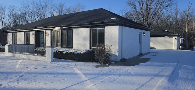 view of snow covered exterior with an outbuilding, a garage, and a porch