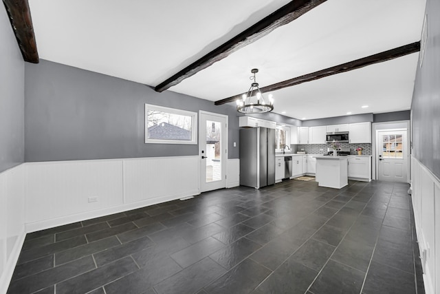 kitchen featuring white cabinetry, hanging light fixtures, a center island, stainless steel appliances, and beam ceiling