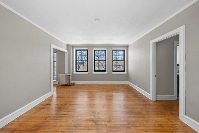 spare room with light wood-type flooring, baseboards, and radiator heating unit