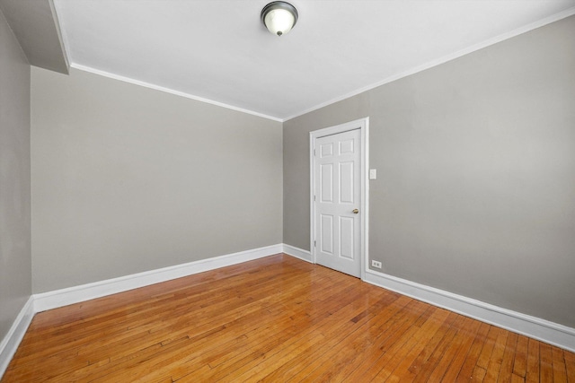 empty room featuring baseboards, crown molding, and hardwood / wood-style floors