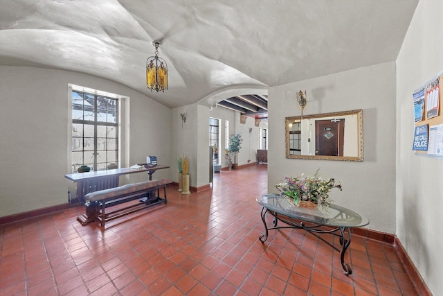 interior space with arched walkways, lofted ceiling, and baseboards