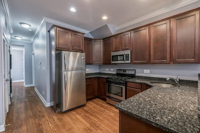 kitchen with sink, crown molding, appliances with stainless steel finishes, dark stone counters, and hardwood / wood-style floors