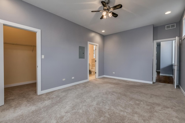 unfurnished bedroom featuring ensuite bath, electric panel, a spacious closet, light colored carpet, and a closet