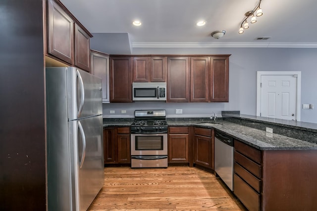 kitchen with sink, dark stone counters, light hardwood / wood-style floors, kitchen peninsula, and stainless steel appliances