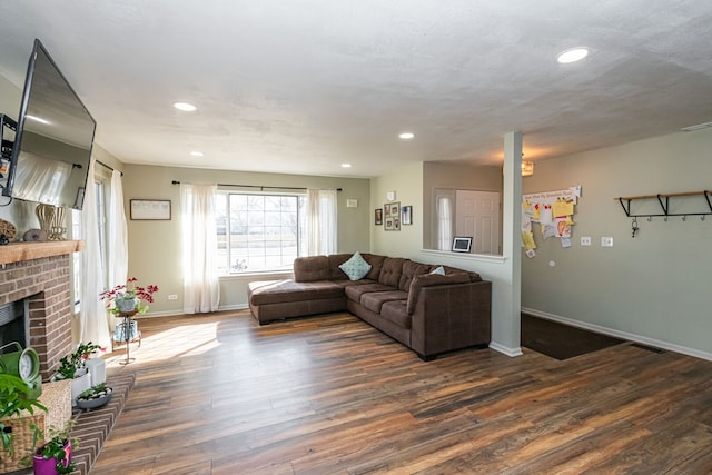 living area featuring visible vents, a brick fireplace, baseboards, recessed lighting, and dark wood-style floors