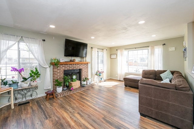 living room with recessed lighting, baseboards, a brick fireplace, and wood finished floors