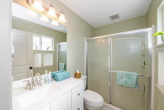 full bathroom with vanity, a shower stall, toilet, and visible vents