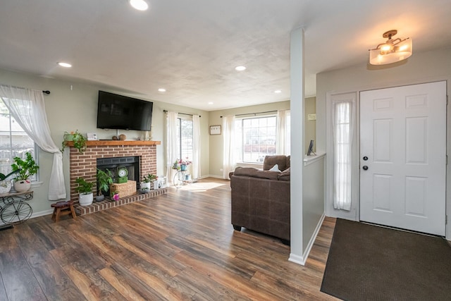 entrance foyer with recessed lighting, a brick fireplace, baseboards, and wood finished floors