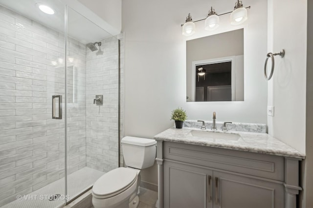 bathroom with a stall shower, vanity, toilet, and baseboards