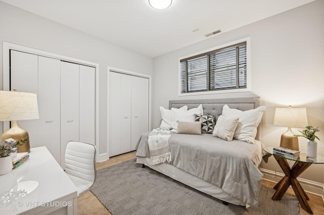 bedroom featuring baseboards, visible vents, and multiple closets