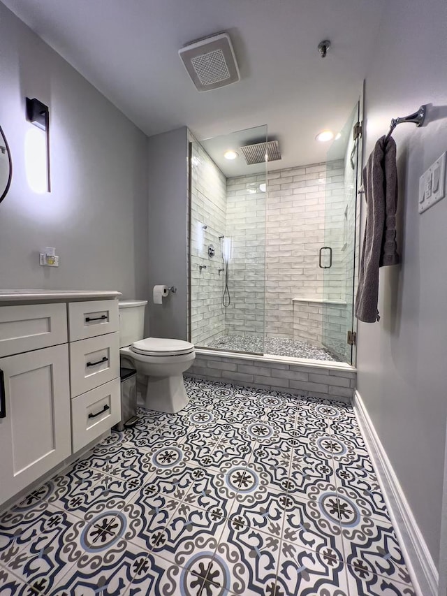 bathroom featuring vanity, a shower with door, tile patterned floors, and toilet