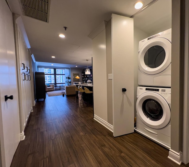 laundry room featuring dark wood-type flooring and stacked washing maching and dryer