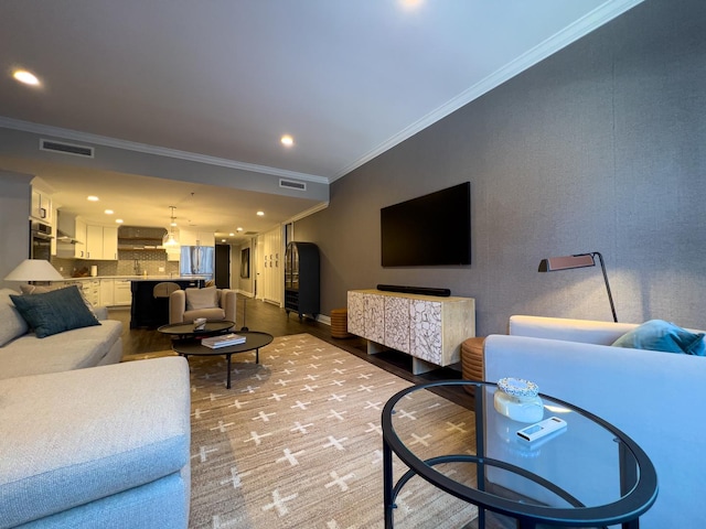 living room featuring hardwood / wood-style floors, crown molding, and sink