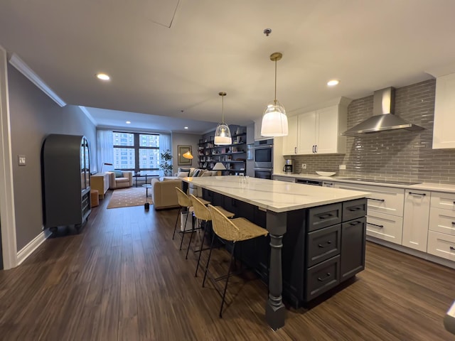 kitchen with a center island, dark hardwood / wood-style floors, a kitchen breakfast bar, wall chimney range hood, and white cabinets