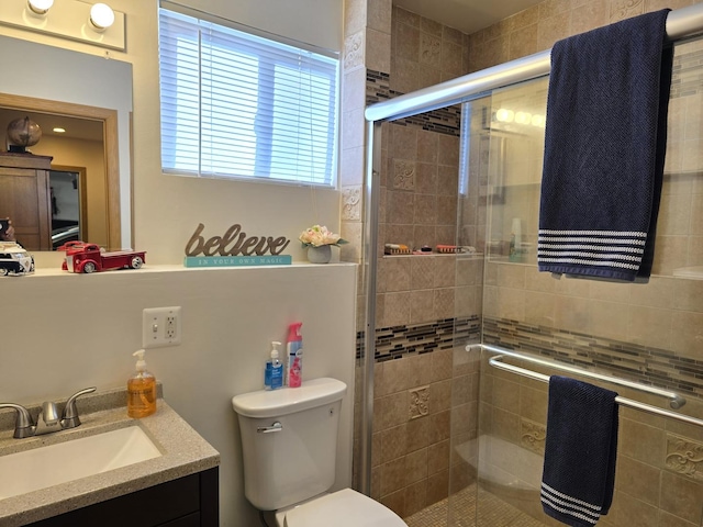 bathroom featuring vanity, a shower with shower door, and toilet