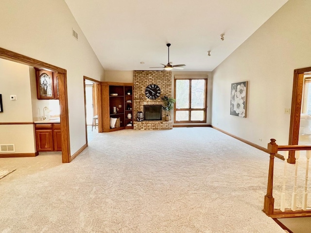 unfurnished living room featuring a brick fireplace, visible vents, and light colored carpet