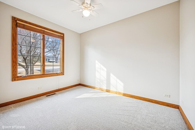 spare room featuring carpet floors, visible vents, baseboards, and a ceiling fan