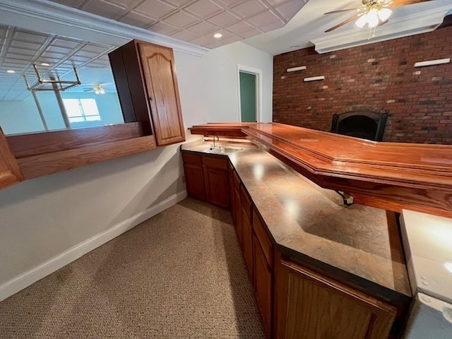 bar featuring brick wall, a sink, a ceiling fan, baseboards, and an ornate ceiling