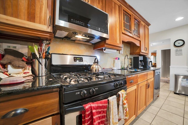 kitchen with dark stone countertops, sink, stainless steel appliances, and light tile patterned flooring