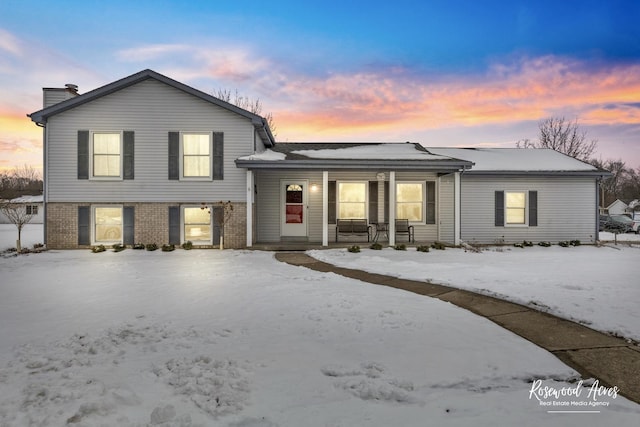 tri-level home featuring brick siding and a porch