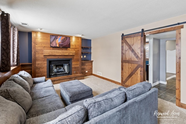 carpeted living area with a barn door, baseboards, visible vents, and a fireplace with raised hearth