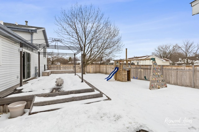 yard layered in snow with a playground and a fenced backyard