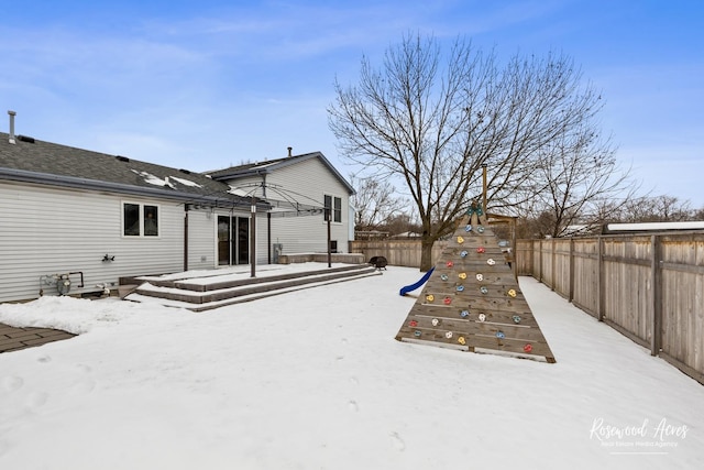 snow covered back of property featuring a fenced backyard