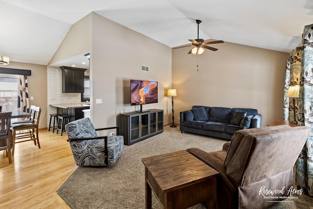 living room with visible vents, high vaulted ceiling, light wood-type flooring, and a ceiling fan