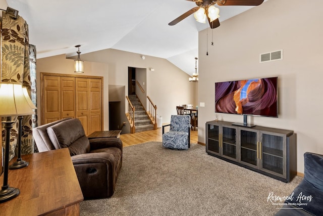 carpeted living room with visible vents, a ceiling fan, baseboards, lofted ceiling, and stairs