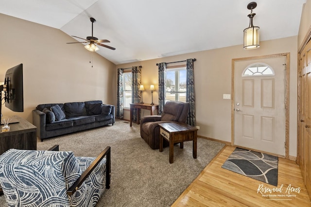 living area featuring a ceiling fan, vaulted ceiling, baseboards, and light wood-type flooring