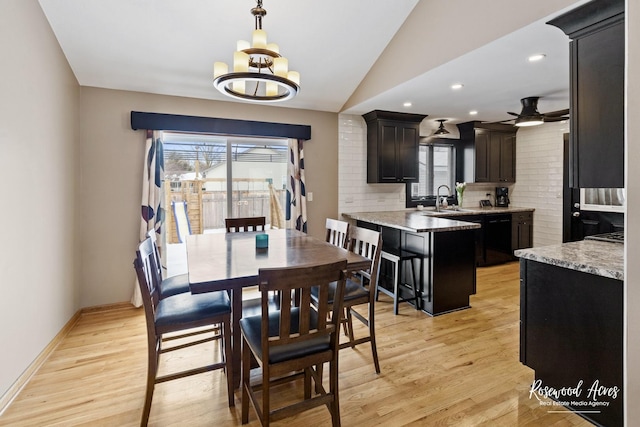 dining space featuring baseboards, lofted ceiling, light wood-style floors, and ceiling fan with notable chandelier